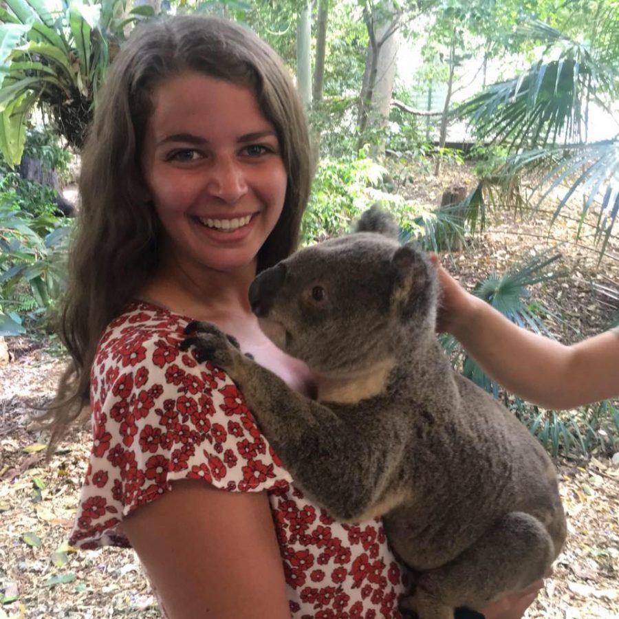 Girl smiling and holding a Koala on her adventures while traveling alone.