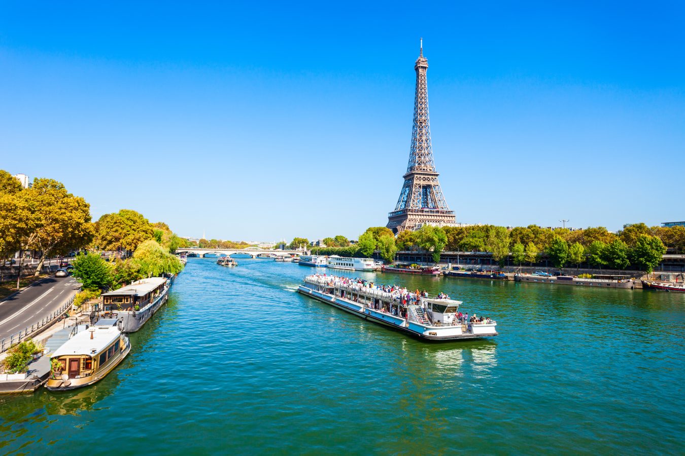 Eiffel Tower in Paris, France with a boat sailing along the Seine River. Paris can be a cheap Europe destination if you plan well.