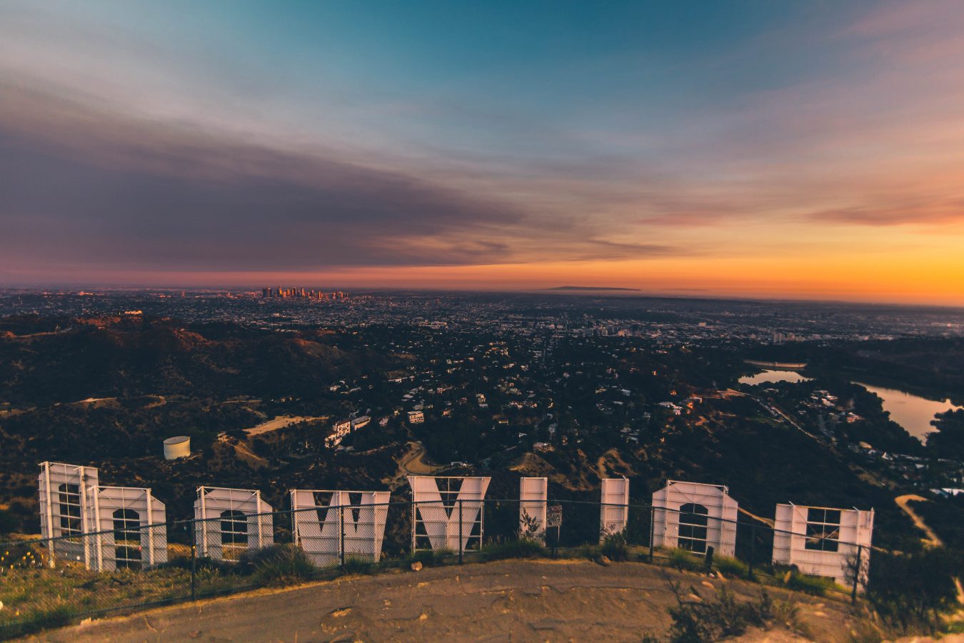 View of Los Angeles from behind the Hollywood sign at sunset. LA is one of the best summer destinations in the us for 2023.