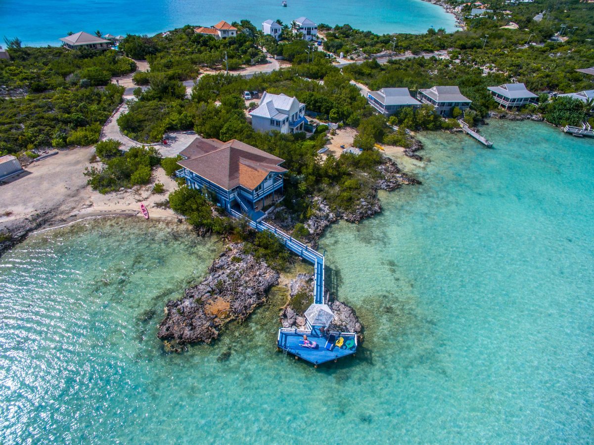 Turks and Caicos waterfront with homes with long docks going into the clear blue water. The islands are a perfect getaway, including for summer 2023.
