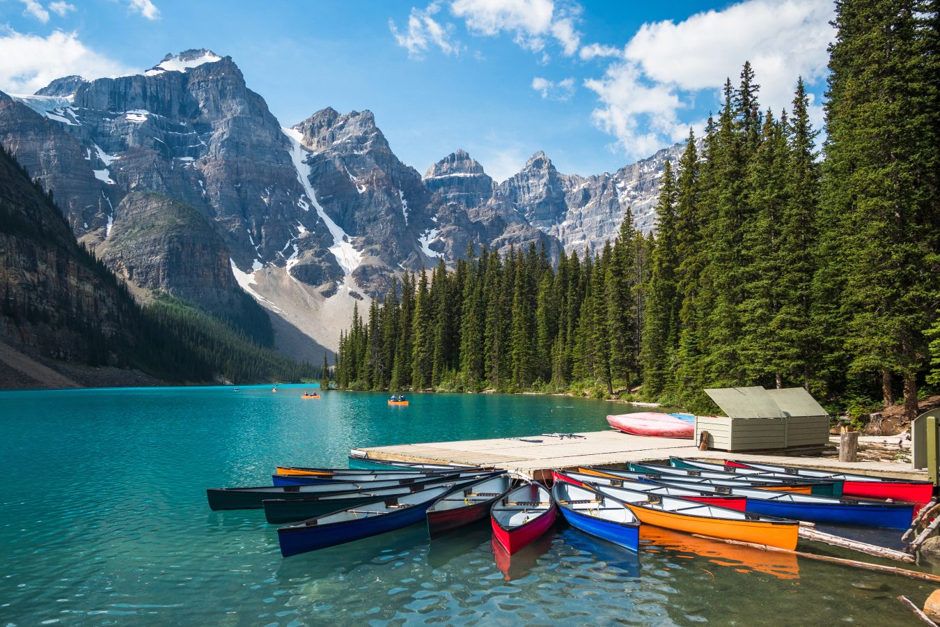 Lake Moraine in Banff National Park, with a bunch of canoes on the dock in the foreground.