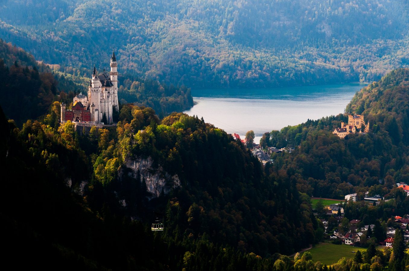 Neuschwanstein Castle on a hill in the Bavarian landscape with lake in background.