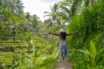 Young black women traveling solo in the jungle of Bali with rice fields around her.