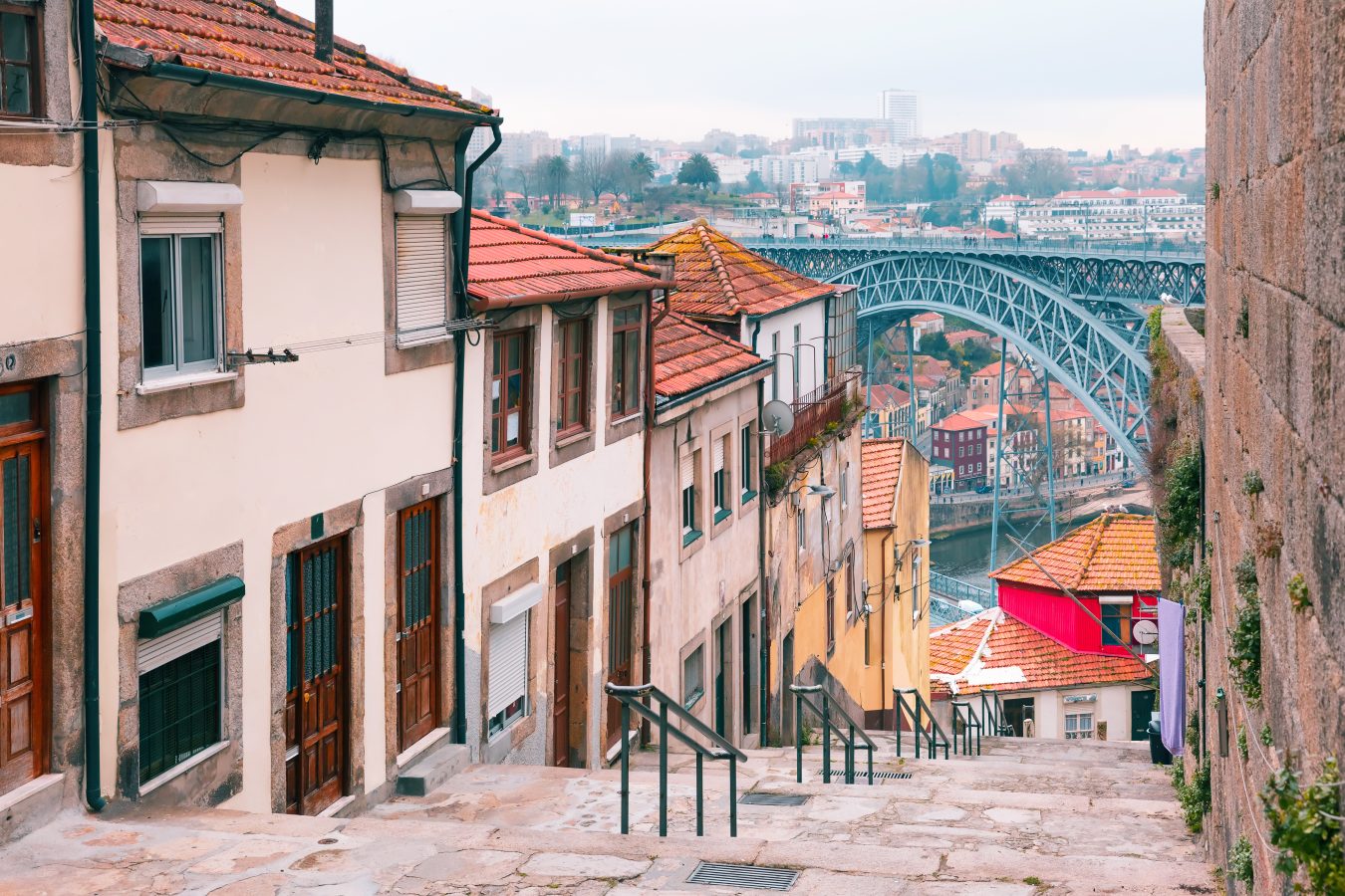 Traditional old houses in Ribeira and stairs down to the river Douro and a bridge the background, of Porto, Portugal
