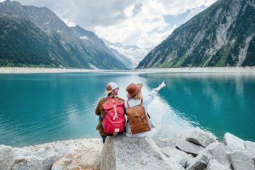 Traveler couple looks at the clear blue lake under mountains in Austria.
