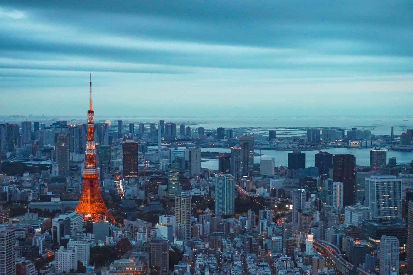 A blue/grey sky with Tokyo tower lit red on the left and surrounded by the skyline of Tokyo, Japan - the destination to travel to for Business majors.
