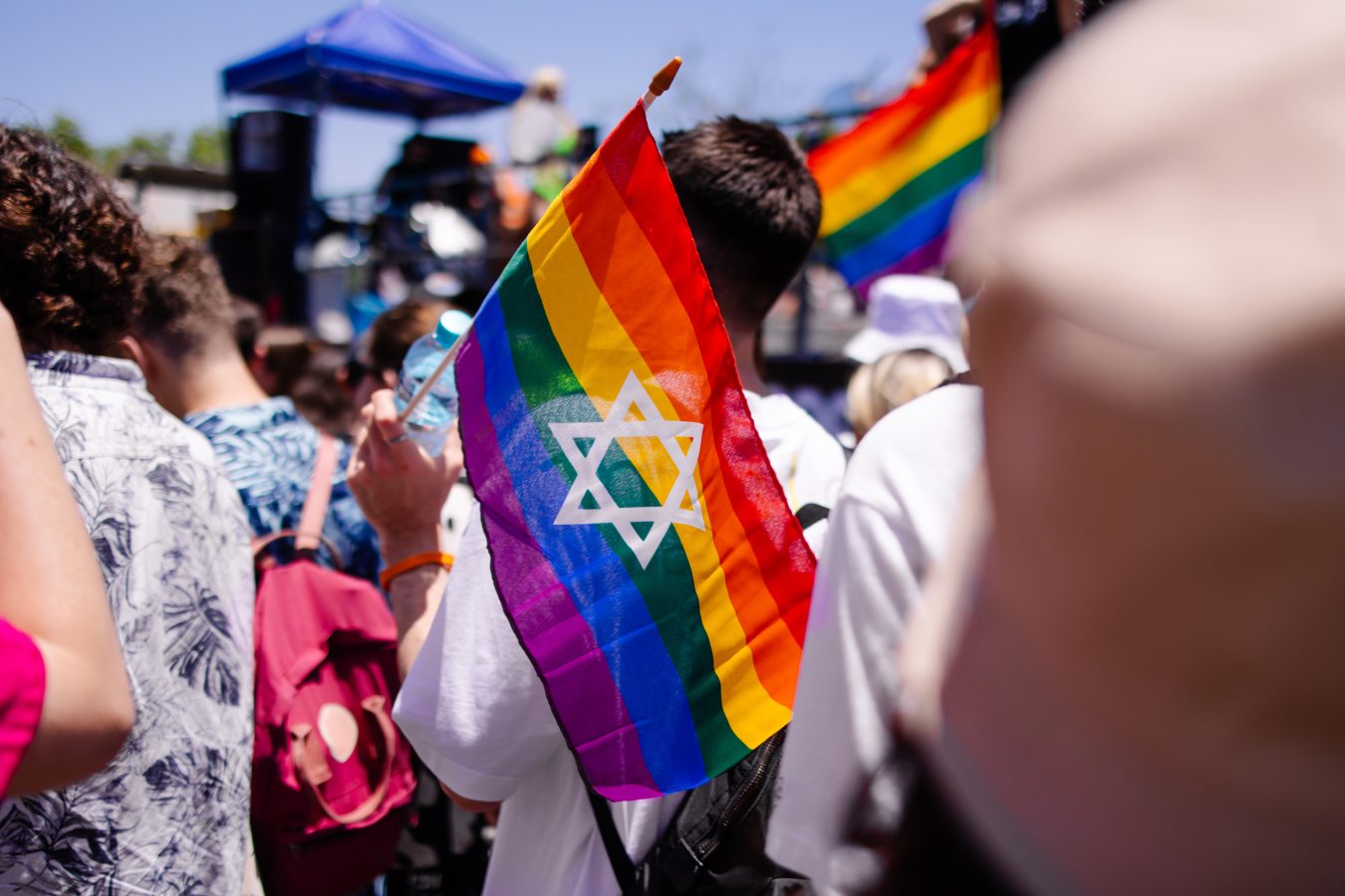 Pride parade in Tel Aviv, Israel, with participants holding rainbow flags with the Star of David.
