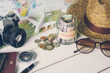 Collecting money for travel with accessories of travel including a hat, sunglasses, camera, compass, model plane, and map.