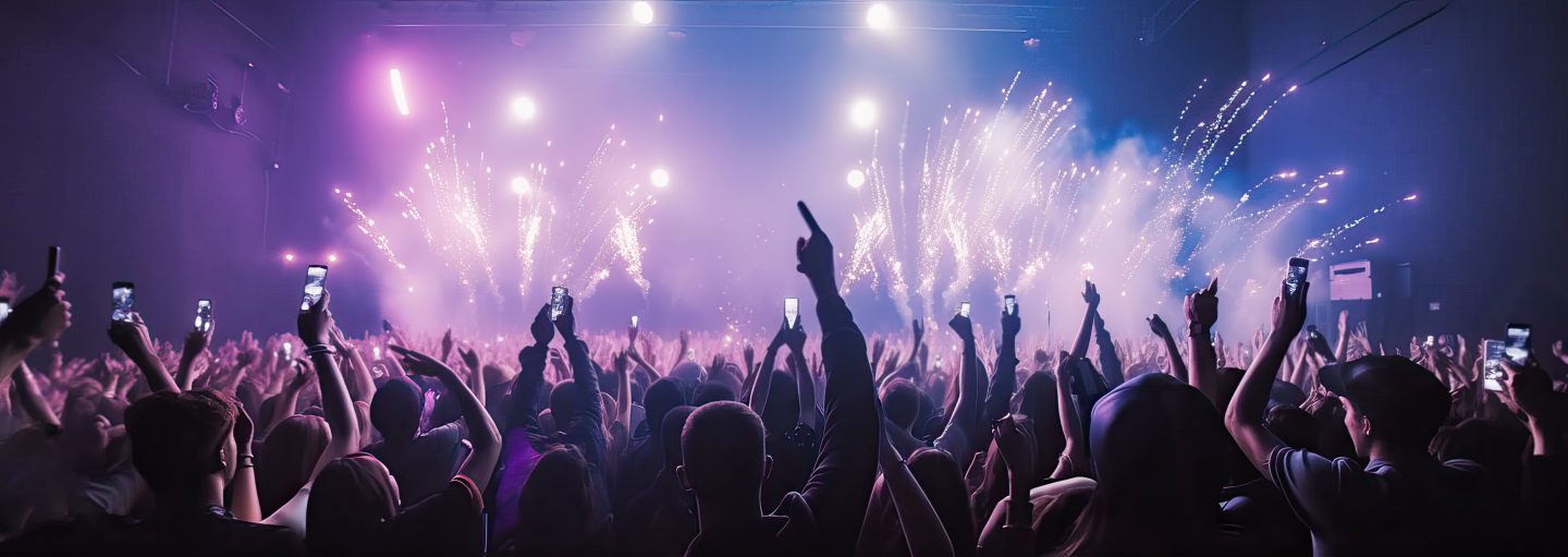 A crowd of people at a live event, concert or party dancing with their hands in the air