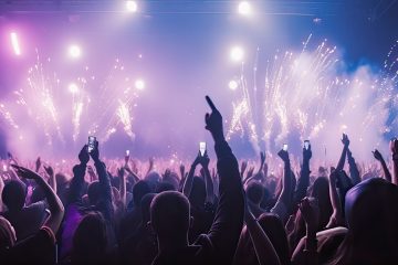 A crowd of people at a live event, concert or party dancing with their hands in the air