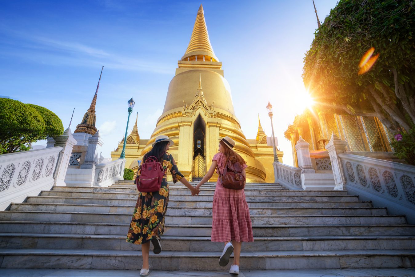 Two travelers hold hands in Grand Palace and Wat phra kaew Bangkok city, Thailand. Thailand's shoulder season is from March to May and from September to November.