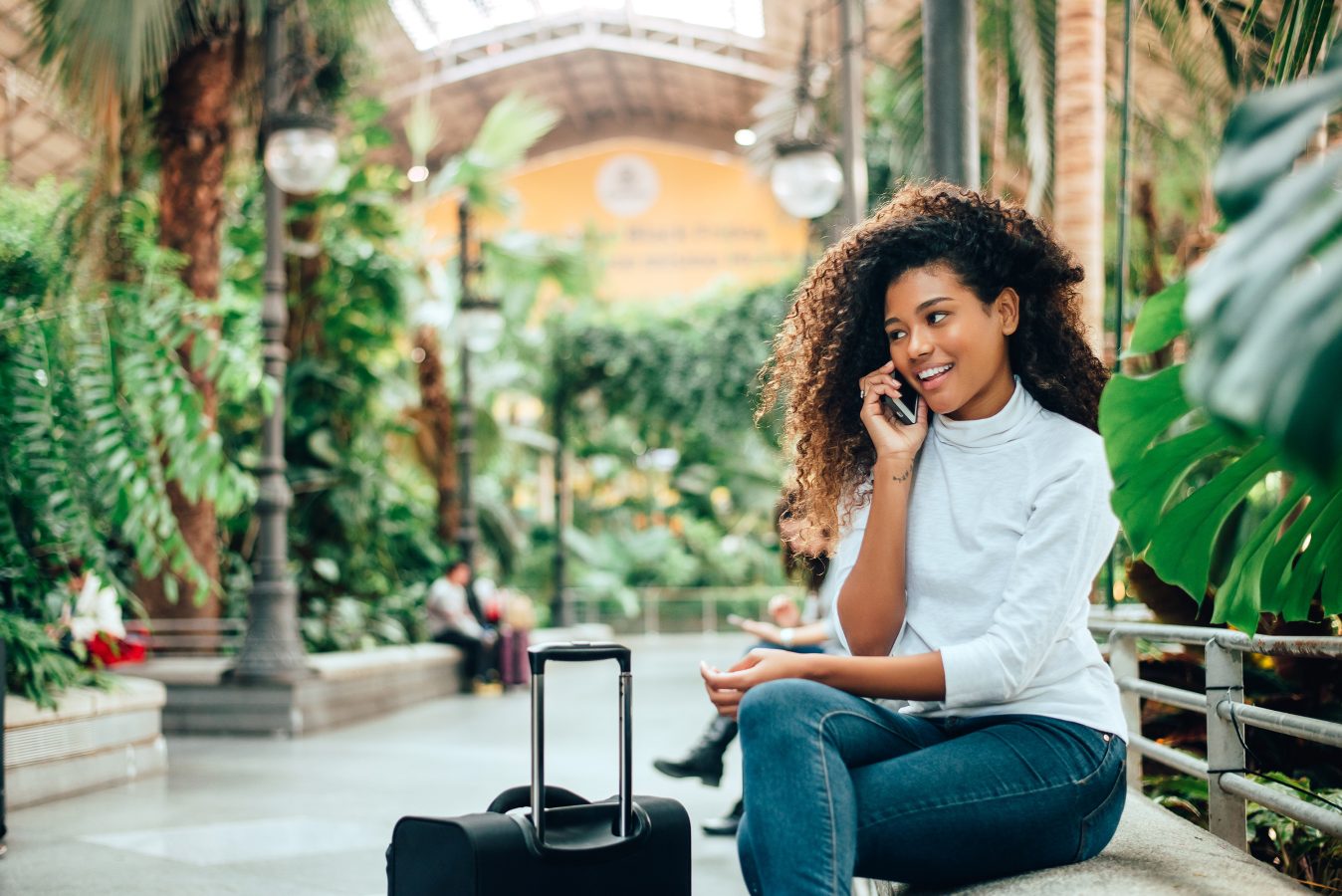 Young woman traveler with her luggage talking on phone.