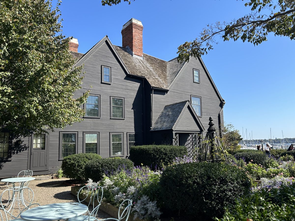 The gardens of the House of the Seven Gables in Salem, MA with part of the house and the harbor behind it.