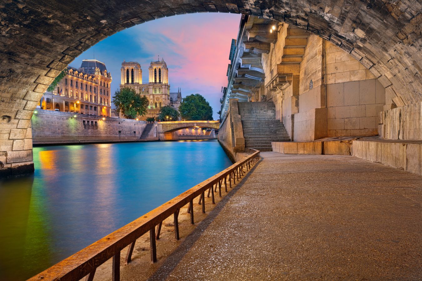 Under a bridge along the Seine River in Paris, France with a new of the Notre Dame in the distance.