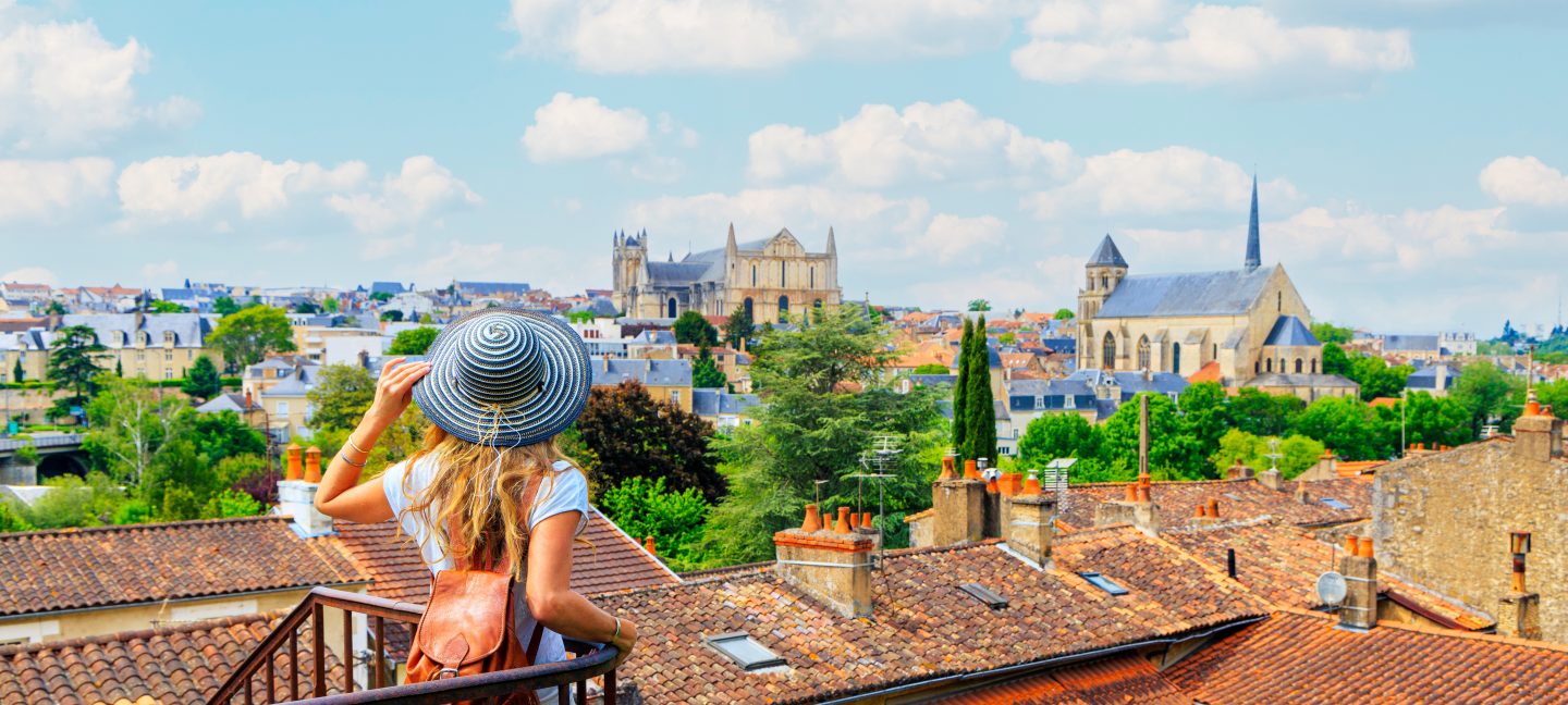 Woman on a solo student travel trip overlooking Poitiers cityscape from a balcony in France.