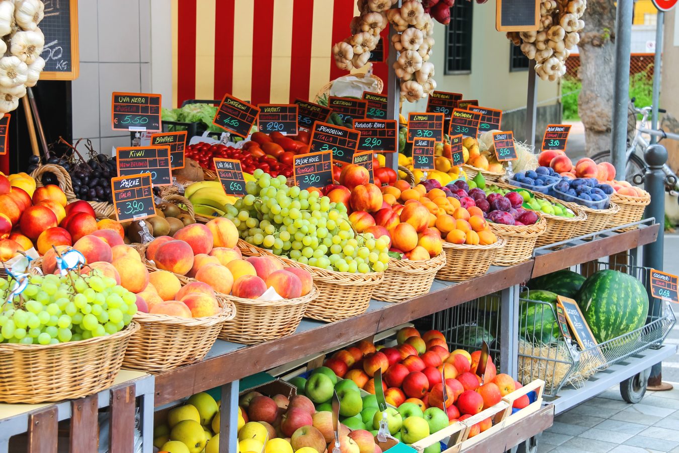 A produce and fruit stall in a street market in an Italian city. Street markets are great spots for travelers to visit when eating on a small student budget. 