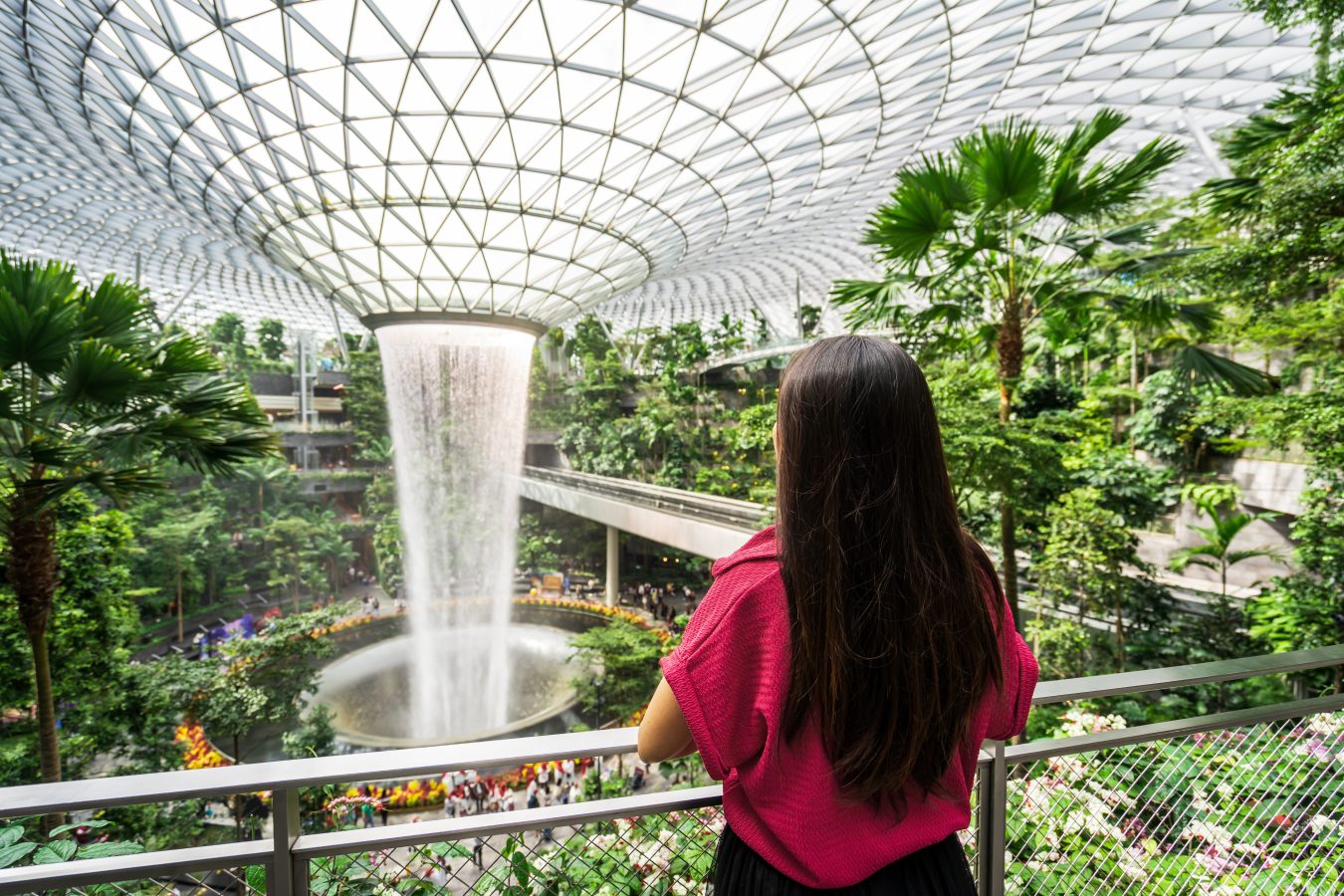 Young female tourist looking at the indoor waterfall in Changi Airport, Singapore.