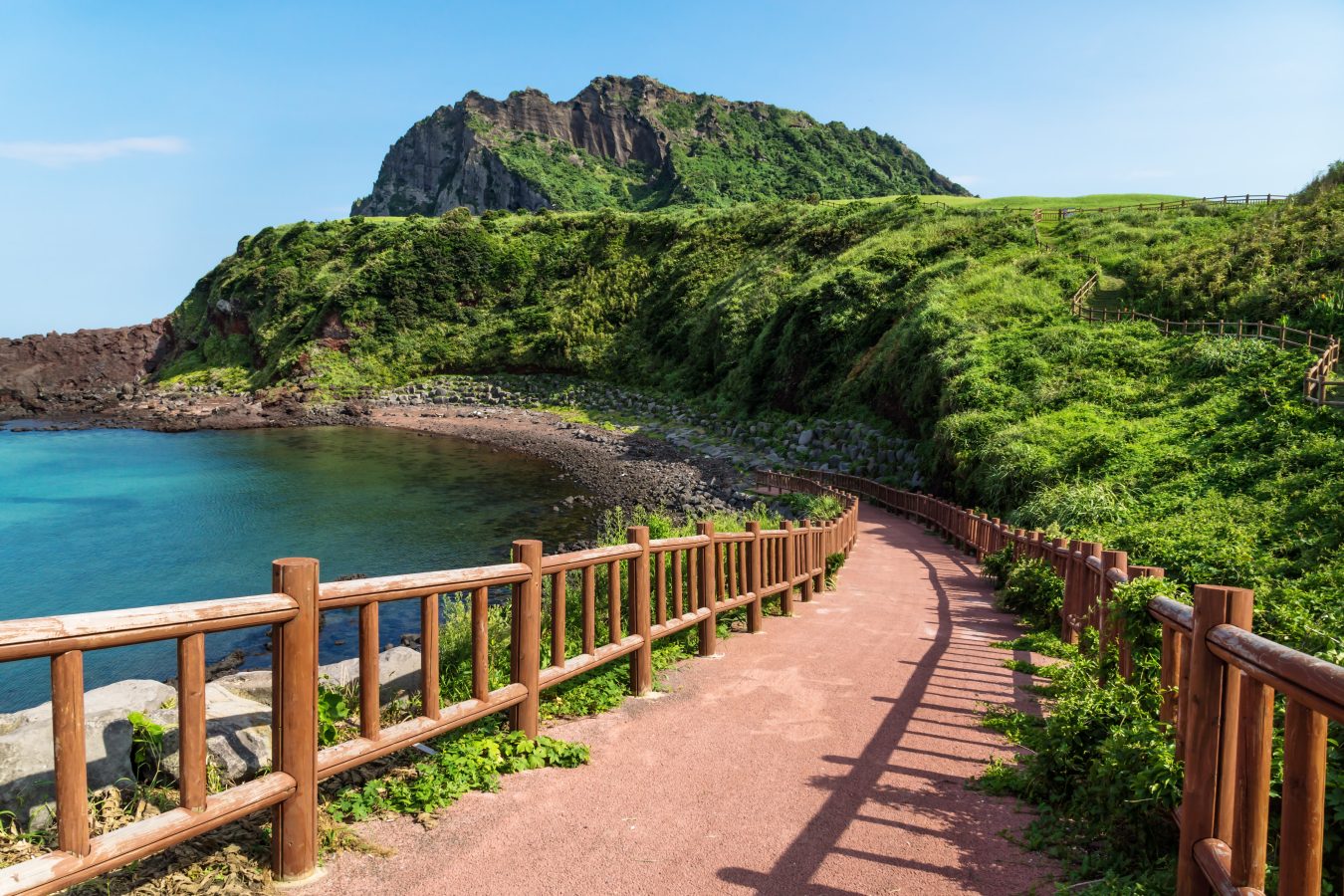 Pathway leading to beach with view over ocean and and volcano crater Ilchulbong, Seongsan, Jeju Island, South Korea.