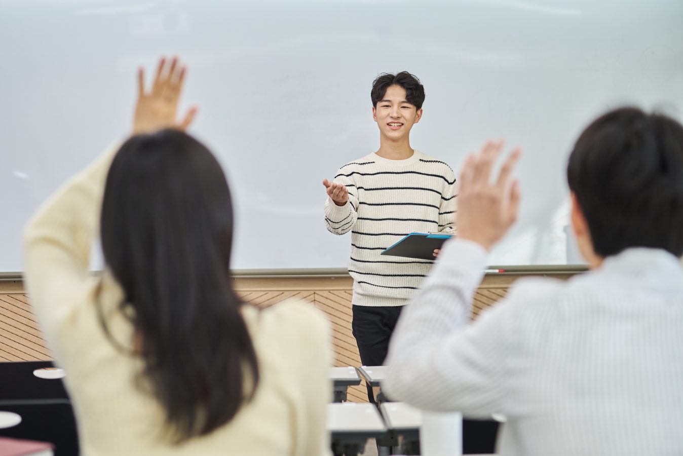 University students raise their hands in a classroom at an asian university.